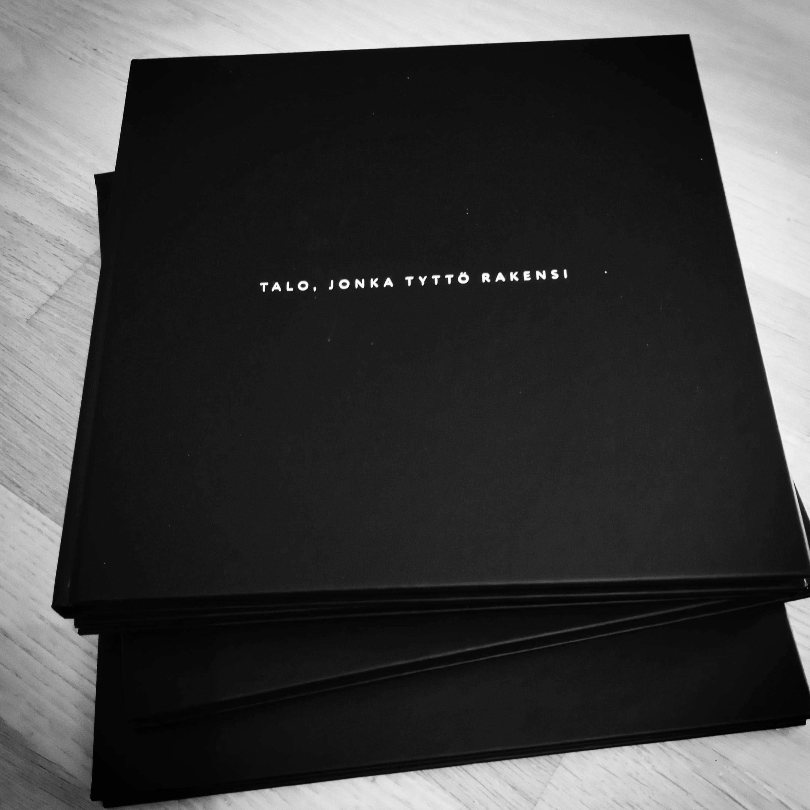A closed black artist’s book with a small white title centered on its cover.