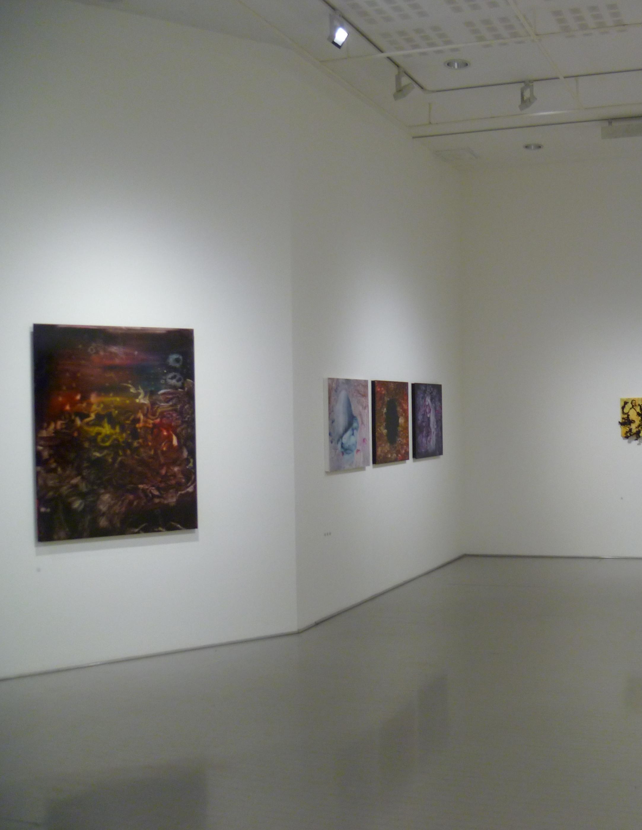 A spare white gallery with one dark painting in the foreground and smaller works beyond.