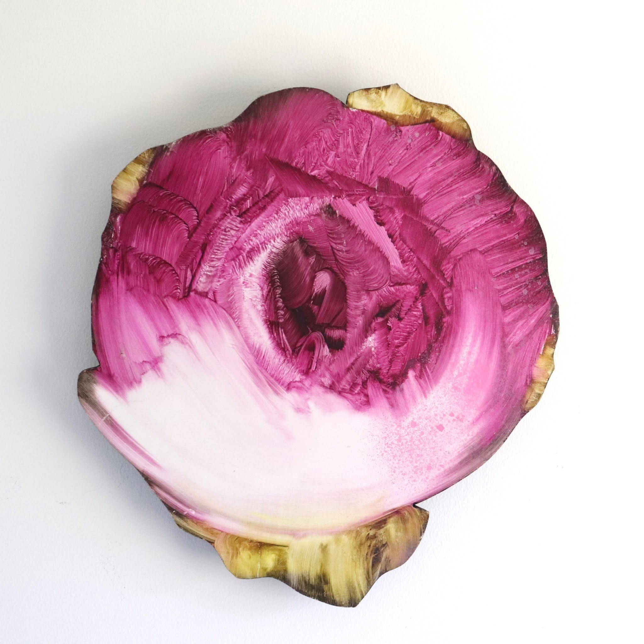 A circular, flower-like painted form in layered pink, cream, and a touch of gold on white.