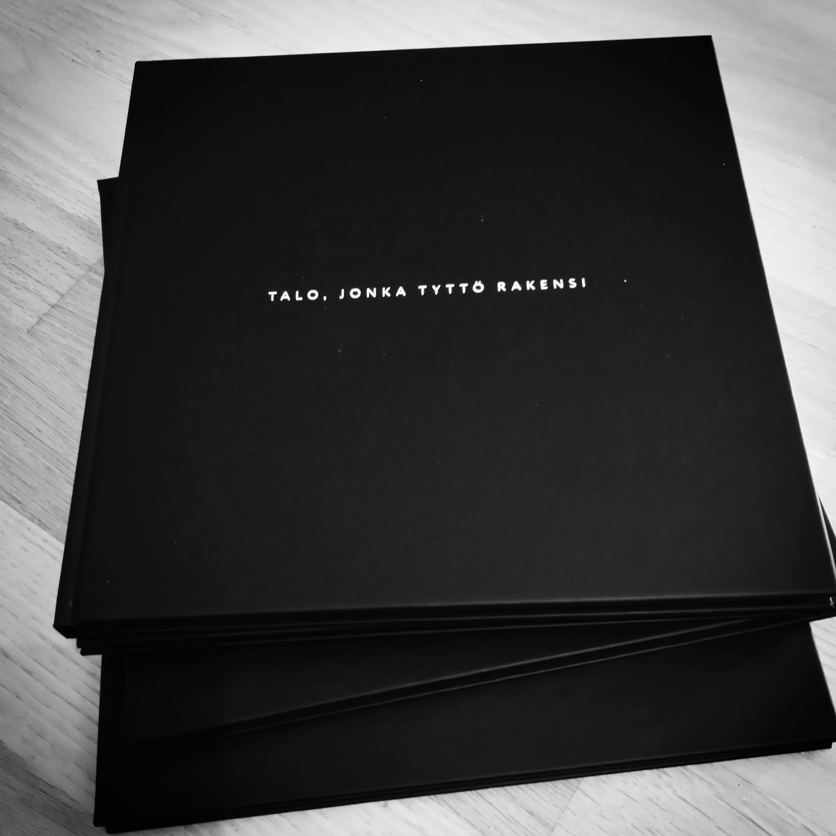 A closed black artist’s book with a small white title centered on its cover.